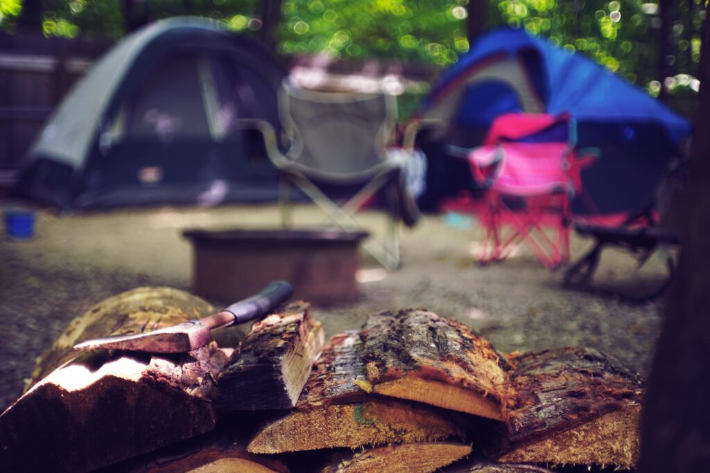 A serene campsite featuring tents, chairs, and a pile of firewood for a perfect summer getaway.